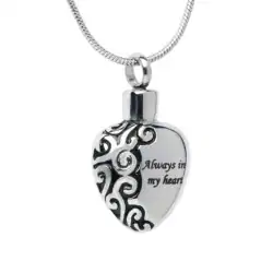 A silver heart-shaped pendant with ornate black swirls and the engraved words "Always in my heart" hangs from a silver chain, a touching keepsake for those seeking pet cremation in Harris County, TX.