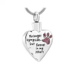 A silver heart-shaped pendant with a small pink paw print and the engraved words "No longer by my side... but forever in my heart," is a touching keepsake for those seeking pet cremation in Harris County, TX.