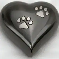 A shiny, metallic heart-shaped object with two raised animal paw prints on its surface, displayed against a soft, light background—an elegant tribute for pet cremation in Harris County, TX.