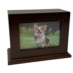 A wooden photo frame displaying a picture of a happy corgi dog sitting on grass, its tongue out and ears perked up—a thoughtful keepsake for those remembering a beloved pet after pet cremation in Harris County, TX.