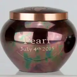 A dark, glossy urn with a rose-gold lid, crafted for pet cremation in Harris County, TX. The word "Pearl" and the date "July 4th 2015" are engraved on the front.