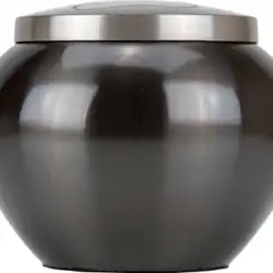 A round, dark metal container with a matching flat lid, reflecting light off its smooth, glossy surface—commonly used for pet cremation in Harris County, TX.