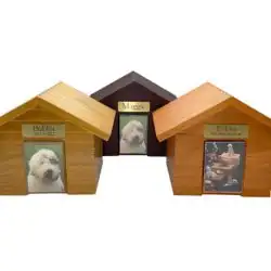 Three wooden dog houses with triangular roofs are shown side by side in TX. Each house features a photo on the front: one of a white dog, one of a white fluffy puppy, and another with a group of dogs at a table—perfect for pet cremation Harris County displays.