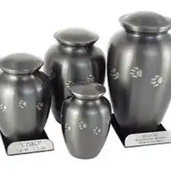 Four metallic urns of varying sizes, each engraved with paw prints and ideal for pet cremation in Harris County, TX, are displayed on a white background. Two urns feature nameplates at their bases.